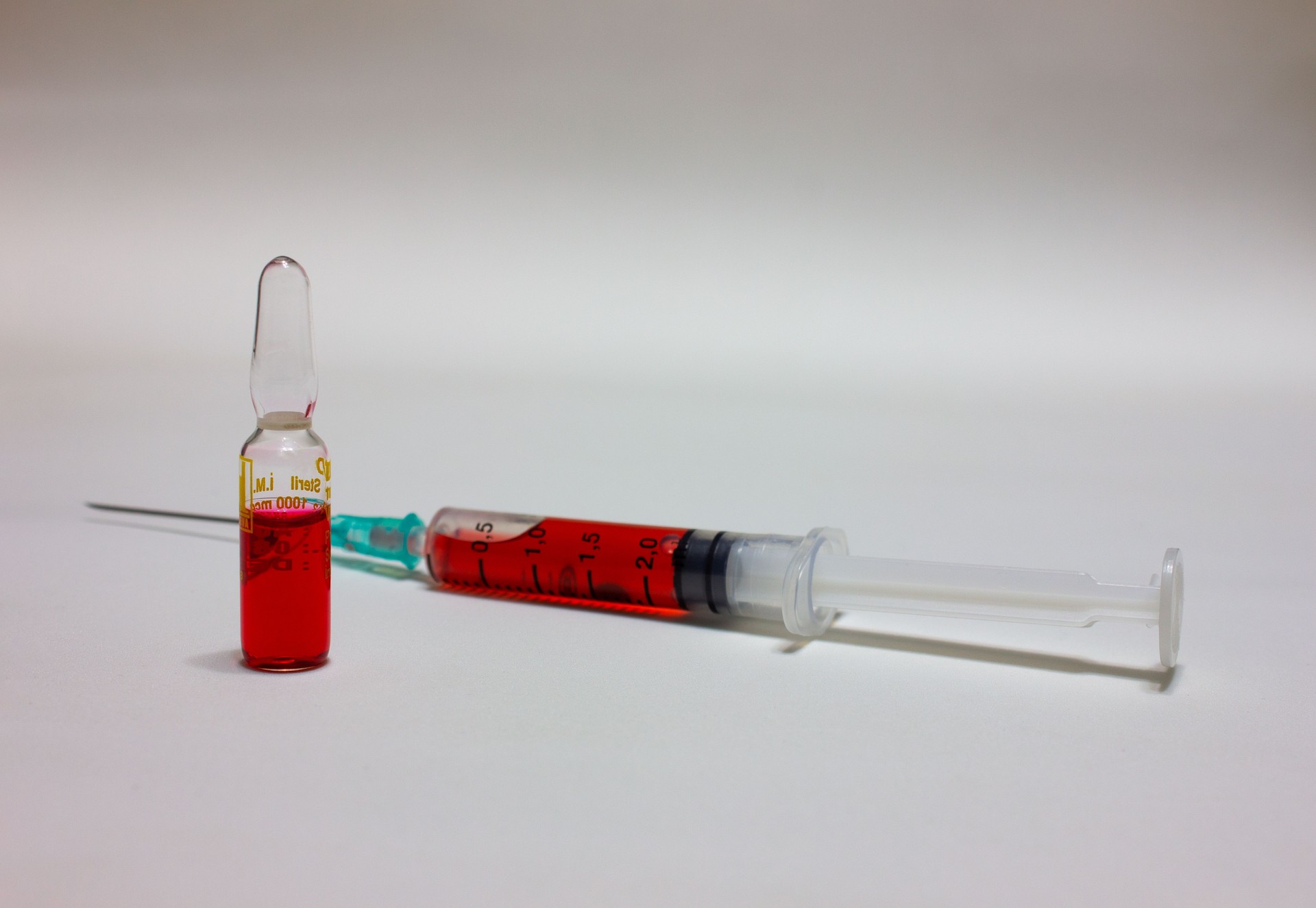 Ampoule medicines and a syringe that full of red medicine. Vaccination and medication concept. Isolated ampoules and vaccine. B vitamins, copy space. B12 medicine.