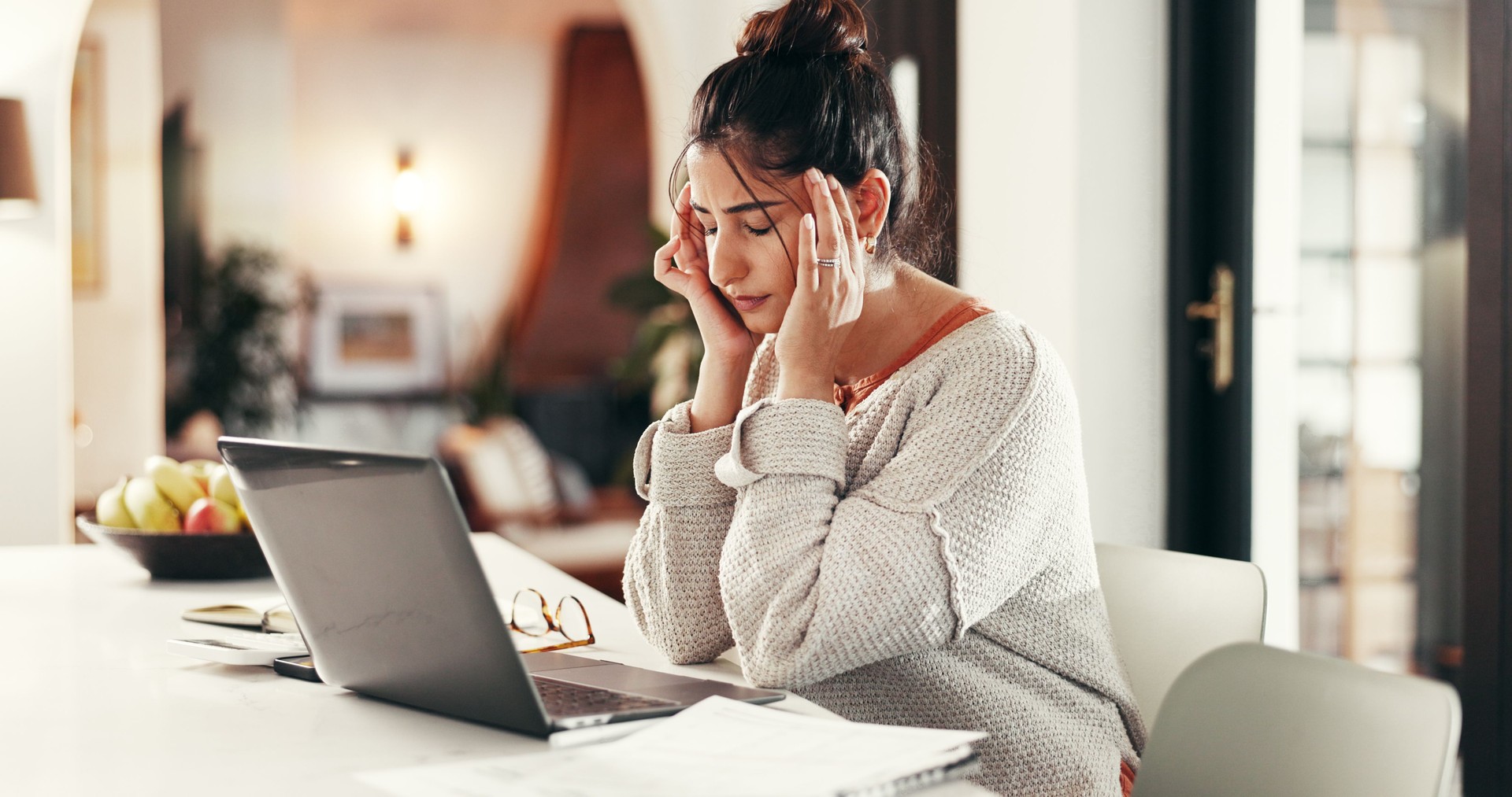 Remote work, pain and woman with headache by laptop, financial crisis and burnout with brain fog. Migraine, sick and freelancer with stress, tired or overworked with fatigue and exhausted in home